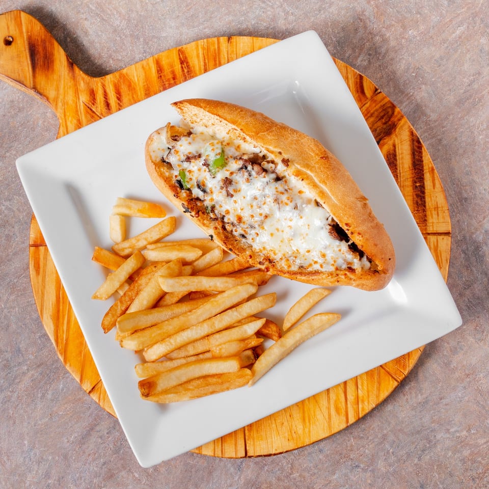 Manhattan Pizza's cheesy steak and pepper sub with a side of golden french fries.