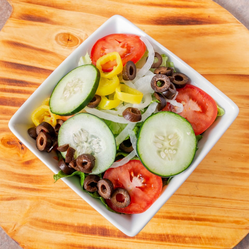 Manhattan Pizza's fresh garden salad with lettuce, tomatoes, cucumbers, onions, banana peppers, and black olives.